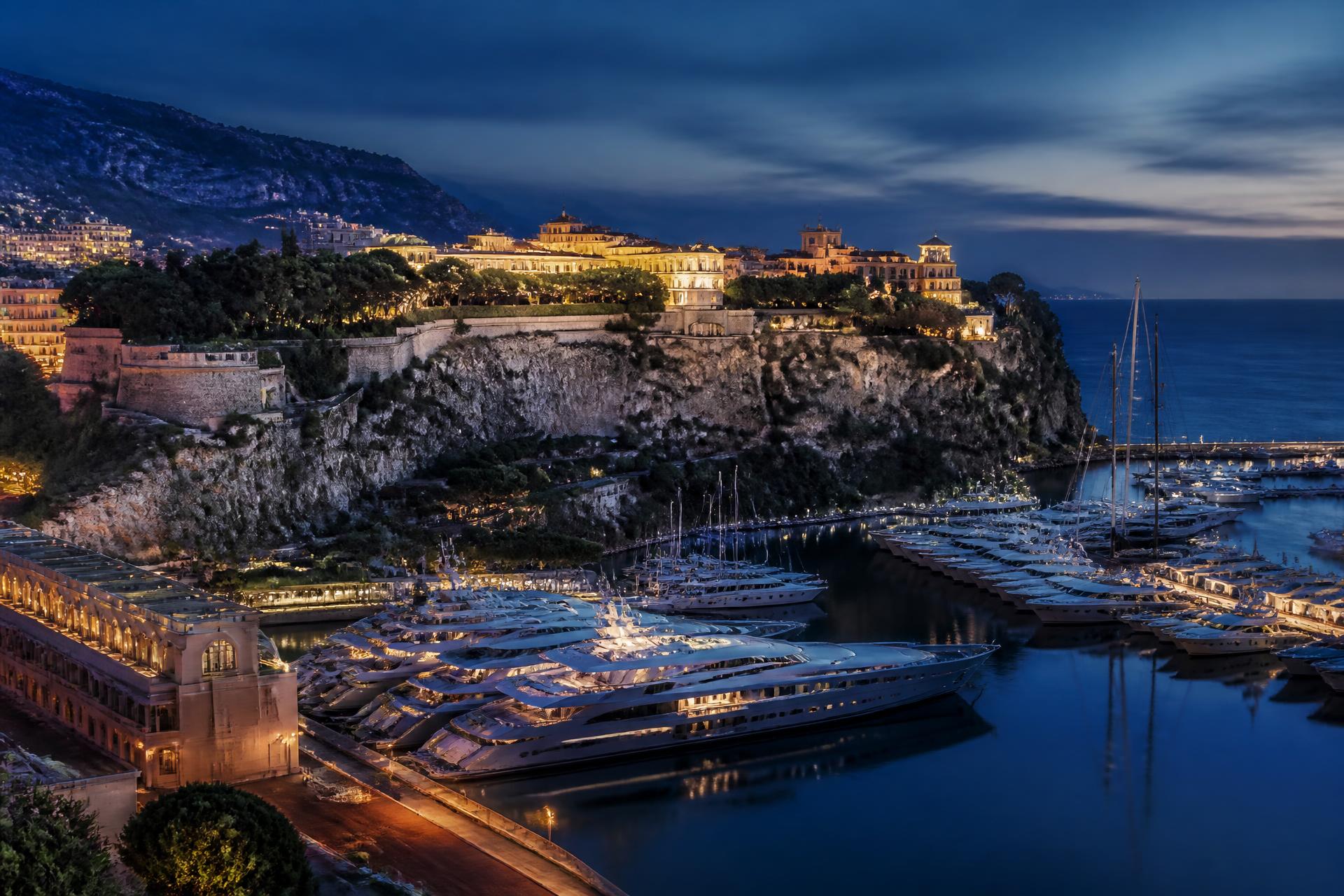 Superyachts moored in Port Hercules with the Monaco skyline at blue hour
